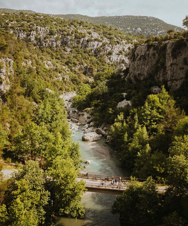 Aerial-view-of-river-and-bridge-in-Taurus-Mountains-Turkey-with-Slow-Cyclists-riding-ebikes